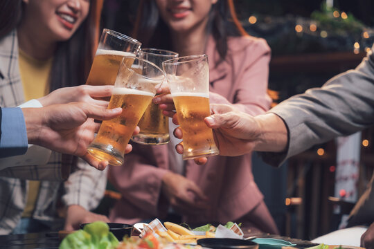 Cheers to Friendship: A group of friends raise their beer glasses in a celebratory toast, capturing the warmth and joy of a shared moment. The scene is filled with laughter and camaraderie. 