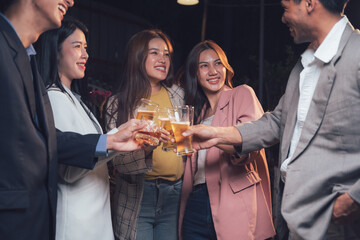 Cheers to Friendship: A group of young professionals raise their glasses in a celebratory toast, their laughter and smiles illuminating the dimly lit scene.