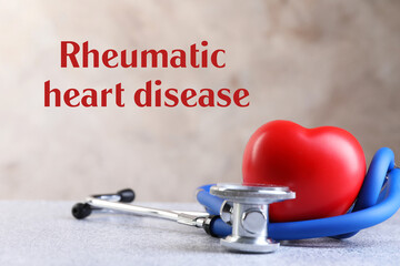 Rheumatism. Stethoscope, red heart and words Rheumatic Heart Disease on blurred background