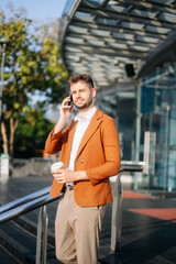 Successful businessman works outdoors near the office holds a tablet