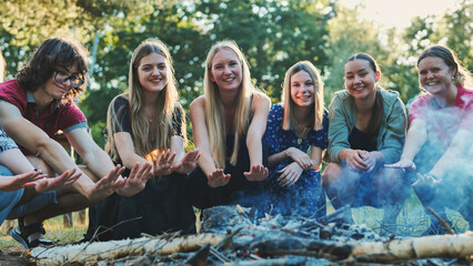 Students huddling around crackling campfire, sharing warmth and camaraderie during woodland summer...