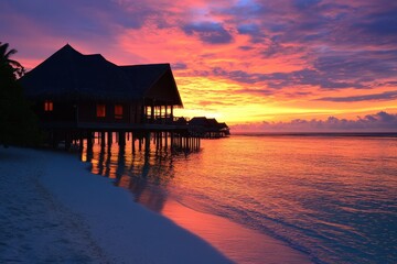 Vibrant sunset over water villas on a tropical beach.