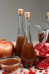 Pomegranate vinegar in a glass bottles among pomegranates.