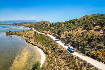 Camper van, RV or motor home is driving on gravel road from Zvernec beach or Dalan beach near Vlore, Albania