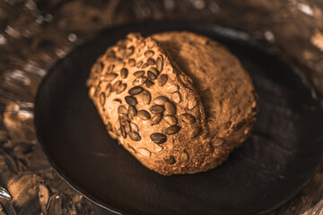 A loaf of rye bread on a black plate on a brown background. Close-up. Top view, space for text