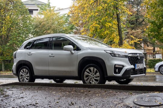 White Suzuki S-Cross III crossover car parked on street in rainy weather