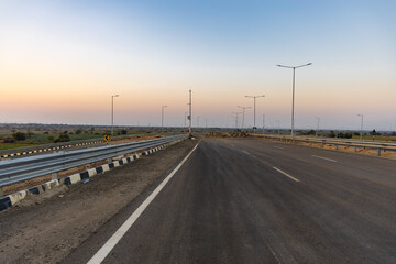 isolated empty tarmac road with bright sunset sky at evening