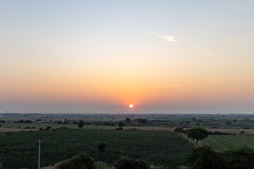 sunset view over hazy city with orange sky and electric pole at dusk