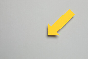 Paper arrow on gray background, top view