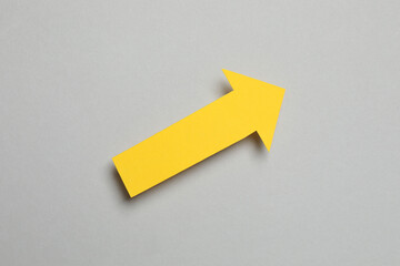 Paper arrow on gray background, top view