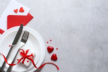 Festive table setting with gift box on gray background. Valentines day dinner concept. View from above. Copy space