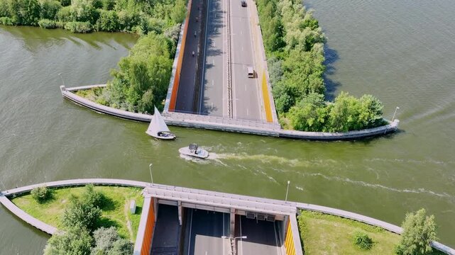 Aquaduct Veluwemeer in the Veluwe lake near Harderwijk where boats pass over the road. A pleasure yacht is sailing over the road where cars cross the water through a tunnel.