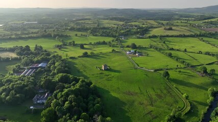 McGrath Castle, Pettigo, County Donegal, Ireland, June 2023. Drone orbits counter clockwise at a high angle around the historic ruined fortress surrounded by vibrant rural greenery on a warm evening.