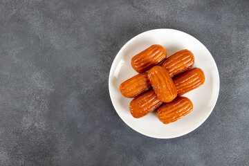 Traditional Turkish dessert tulumba on a plate. Tulumba dessert, fried in oil and soaked in syrup 