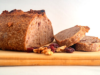 Pan de masa madre perfectamente horneado con nueces y arándanos, presentado sobre una tabla de madera / Perfectly baked sourdough bread with walnuts and cranberries, presented on a wooden board