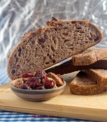 Pan de masa madre perfectamente horneado con nueces y arándanos, presentado sobre una tabla de madera / Perfectly baked sourdough bread with walnuts and cranberries, presented on a wooden board