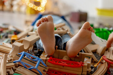 Child, cute boy, playing with toys in a playroom, focus on his feet