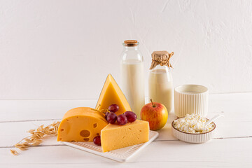 cheese, bottles of milk, grapes, an apple, a vase with ears of wheat on a wooden table. Traditional treats and symbols of the Shavuot. Front view.