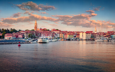 Fototapeta premium Stunning evening cityscape of old fishing town - Isola. Wonderful summer seascape of Adriatic Sea. Amazing sunset in Slovenia, Europe. Traveling concept background.