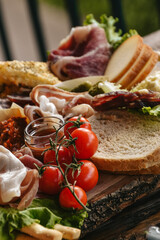 Traditional italian appetizers (antipasto). Salami, prosciutto, cheese, sticks of bread and tomatoes served on the wooden board. Dinner or aperetif party concept.