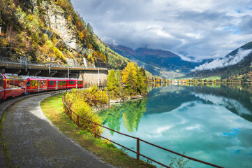 Red Train on Bernina Express Route Along Lake Miralago in Swiss Alps, Val Poschiavo in the canton of Graubunden, Switzerland.