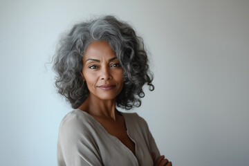 Fototapeta premium A beauty portrait of an elderly African American woman with elegant, graying curls and a serene expression, wearing a neutral-colored blouse, on a white background