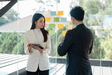 Diverse business professionals brainstorming ideas using sticky notes in a modern office, highlighting collaboration and creativity.