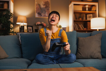 Obraz premium Woman playing video games at home celebrating after winning