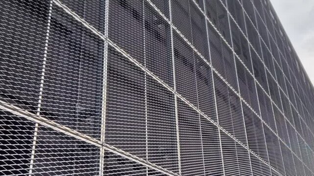 steel cladding of a building with a expanded metal lattice structure. galvanized gray nets protect the industrial building. Blue sky in contrast to a silver background, wall
