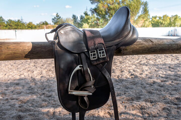 Leather saddle with stirrups for show jumping race. Saddle for riding horse. Horse saddle on rural...