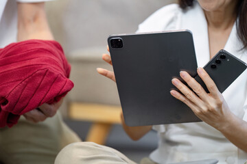 Diverse couple planning travel itinerary on a tablet while holding a red blanket, showcasing modern travel preparation.