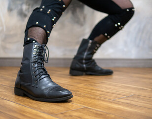 A man in rock clothes performs dance moves. A metal man with a mohawk on his head. Man in motion and gestures of arms and legs in dance.