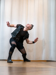 A man in rock clothes performs dance moves. A metal man with a mohawk on his head. Man in motion...