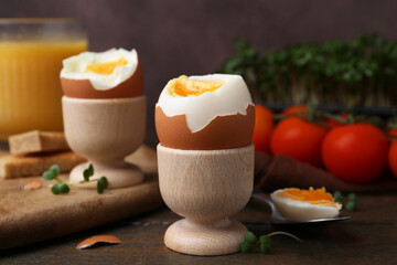 Soft boiled eggs, microgreens and tomatoes on wooden table, selective focus