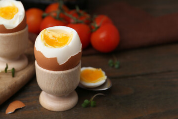 Soft boiled eggs and tomatoes on wooden table, selective focus. Space for text