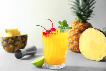 Tasty pineapple cocktail with mint and cherry in glass served on light table