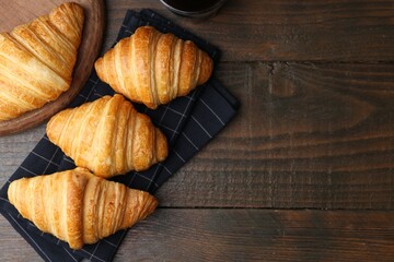 Tasty fresh croissants on wooden table, flat lay. Space for text