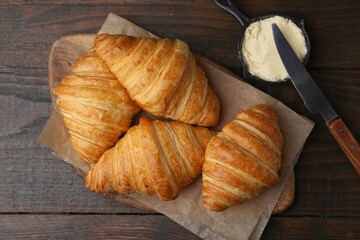 Tasty fresh croissants served with butter on wooden table, flat lay