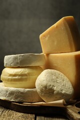 Different types of cheese on wooden table against grey background, closeup