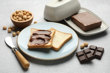 Sandwiches with chocolate butter, hazelnuts and knife on grey table, closeup