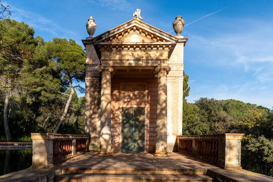 A neoclassical pavilion with a grand entrance, featuring decorative urns, columns, and intricate stone details.