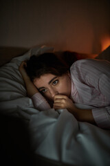 Obraz premium Emotions of solitude expressed by a woman lost in thought at night in a dimly lit room