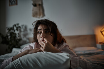 Lost in thoughts the woman gazes out from her dimly lit bedroom enveloped in introspection