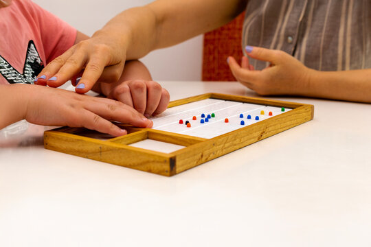 Hands in close up.  The hands of a girl and the hands of a teacher in close-up. Braille board for learning alphabet.