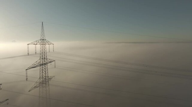 Wind wheel and pylons over clouds with the sun