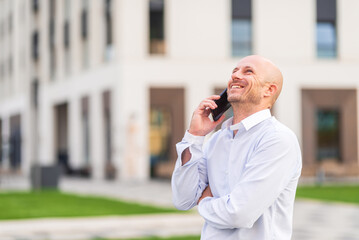 Happy businessman talking on the phone in the city