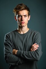 Naklejka premium Grumpy young man crossing arms showing disapproval on dark background