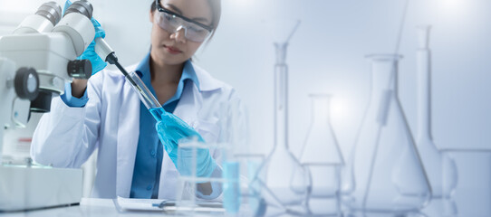 Asian Researcher using a microscope in the clinical lab.Female Researcher working in the clinical...