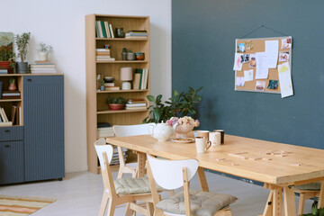 Wide shot of spacious living room equipped with wooden furniture and wooden table with tea set and...