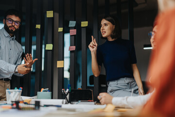 A diverse group of business people engages in a brainstorming session, analyzing ideas and...